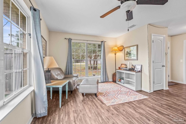 living area with wood-type flooring, ceiling fan, and a textured ceiling