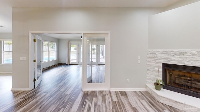 unfurnished living room with hardwood / wood-style floors, a fireplace, and french doors