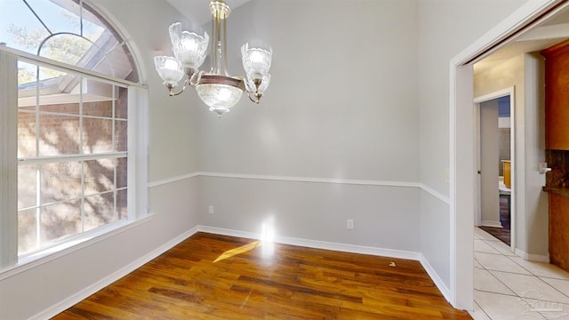 unfurnished dining area with light wood-type flooring and a notable chandelier