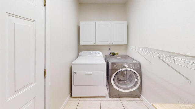 clothes washing area with light tile patterned flooring, cabinets, and independent washer and dryer