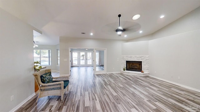 living room with ceiling fan, french doors, wood-type flooring, vaulted ceiling, and a fireplace