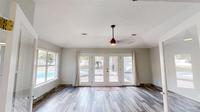 doorway to outside with a healthy amount of sunlight, vaulted ceiling, a textured ceiling, and french doors