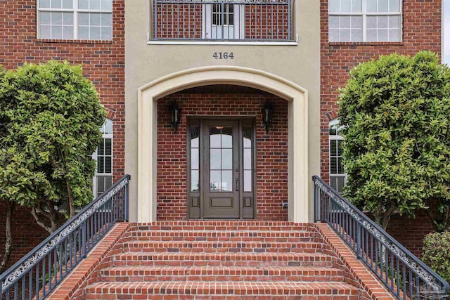 property entrance with brick siding and stucco siding