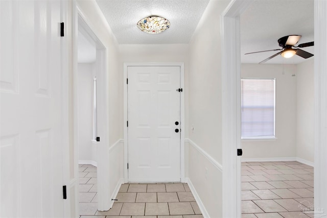 tiled entrance foyer with ceiling fan and a textured ceiling