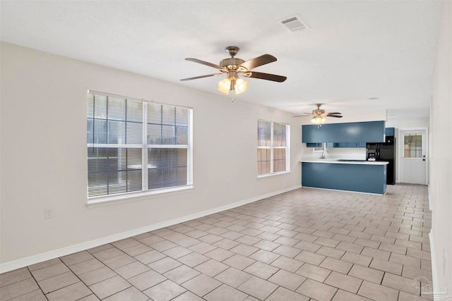 unfurnished living room featuring ceiling fan, sink, and light tile patterned floors