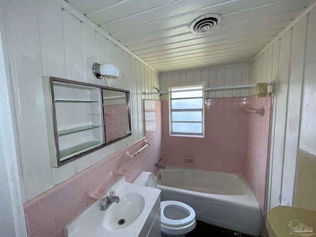 full bathroom with vanity, tile walls, tiled shower / bath combo, toilet, and backsplash