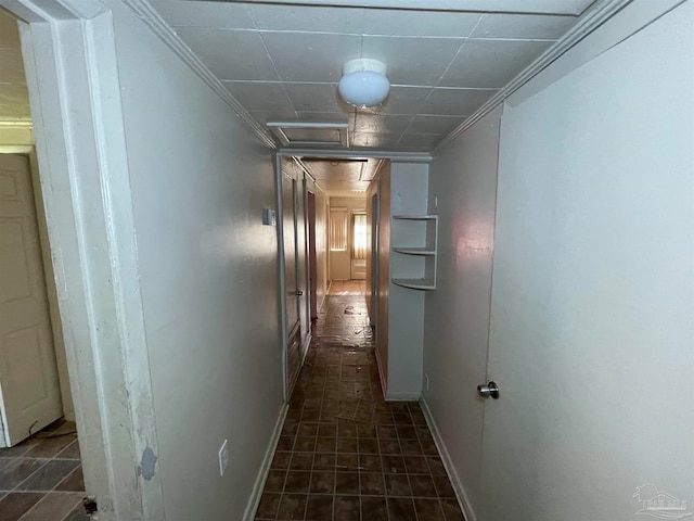 hallway with dark tile patterned floors and crown molding