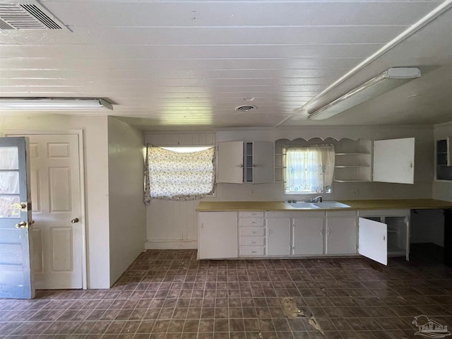 kitchen with sink, dark tile patterned floors, and white cabinets