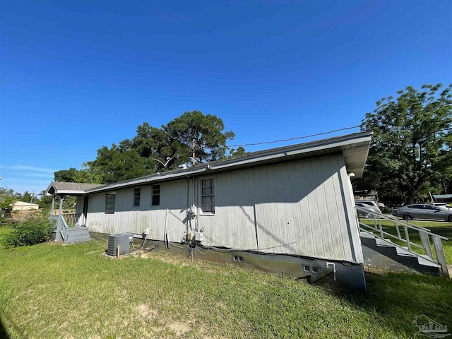 rear view of house featuring central air condition unit and a lawn