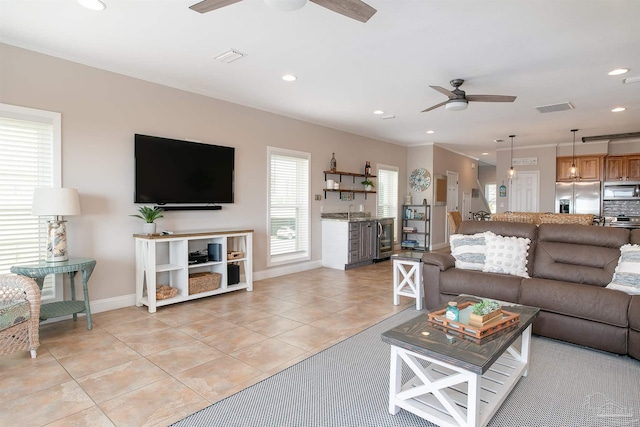 living area featuring light tile patterned flooring, ceiling fan, visible vents, and baseboards
