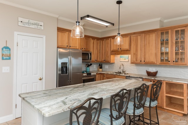 kitchen featuring decorative backsplash, a sink, appliances with stainless steel finishes, and a breakfast bar area
