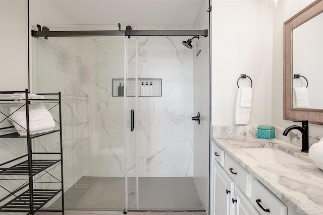 full bath featuring a marble finish shower and vanity