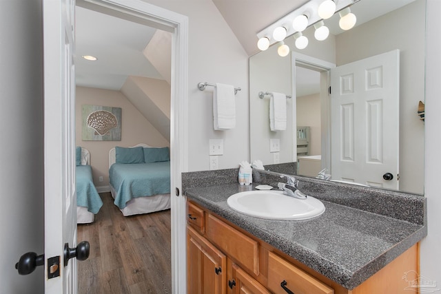 ensuite bathroom featuring wood finished floors, ensuite bathroom, lofted ceiling, and vanity