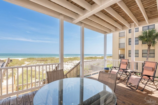 wooden deck featuring a water view, outdoor dining area, and a view of the beach