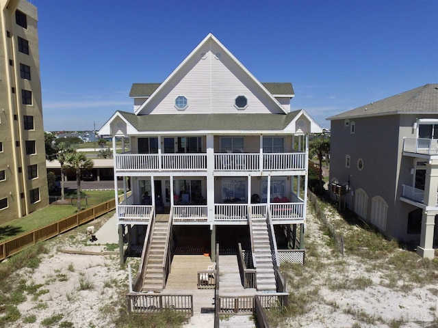 rear view of property featuring stairs, a shingled roof, and a balcony