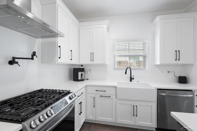 kitchen with wall chimney exhaust hood, stainless steel appliances, sink, and white cabinets