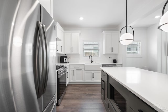 kitchen with white cabinetry, stainless steel appliances, sink, and hanging light fixtures