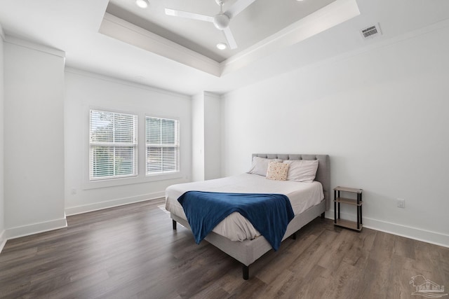 bedroom featuring ceiling fan, dark hardwood / wood-style flooring, and a tray ceiling