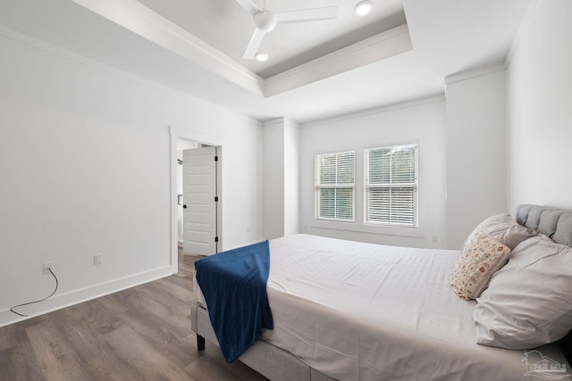 bedroom featuring a tray ceiling, dark hardwood / wood-style floors, and ceiling fan