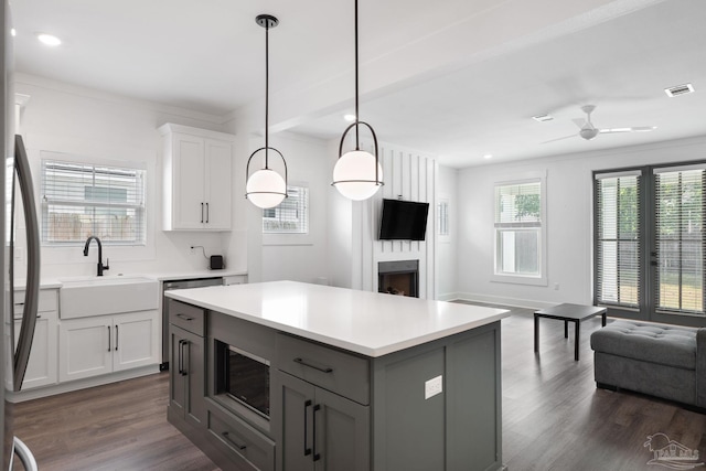 kitchen with sink, white cabinetry, decorative light fixtures, a center island, and dark hardwood / wood-style flooring