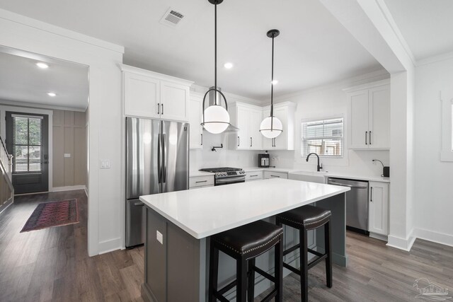 kitchen featuring white cabinetry, appliances with stainless steel finishes, a center island, and hanging light fixtures