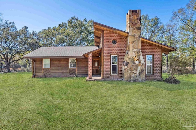 view of front of property featuring brick siding, a chimney, and a front yard