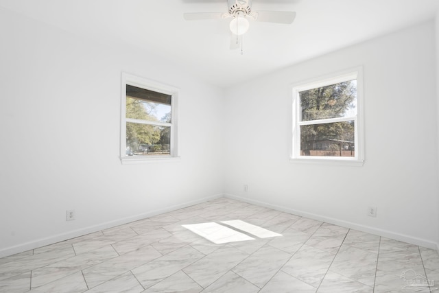 spare room featuring ceiling fan and baseboards