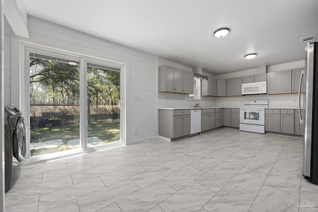 kitchen with white appliances, washer / clothes dryer, light countertops, and gray cabinetry