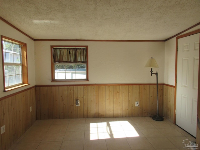 empty room featuring crown molding, wainscoting, wood walls, and a textured ceiling