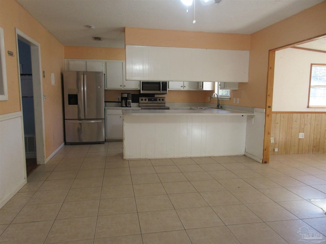 kitchen featuring a peninsula, white cabinets, stainless steel appliances, and light countertops