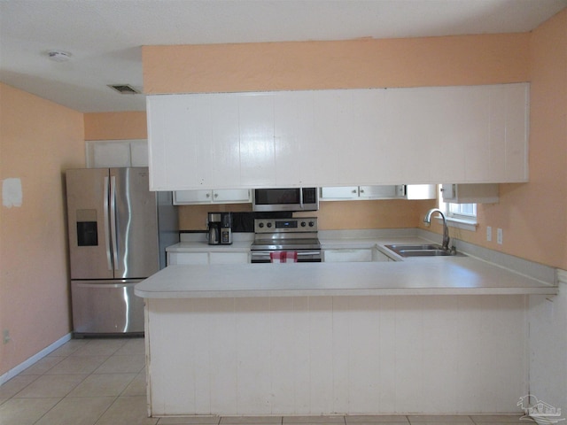 kitchen with light countertops, appliances with stainless steel finishes, white cabinetry, a sink, and a peninsula