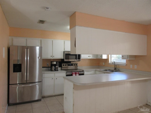 kitchen featuring appliances with stainless steel finishes, light countertops, a peninsula, and white cabinetry