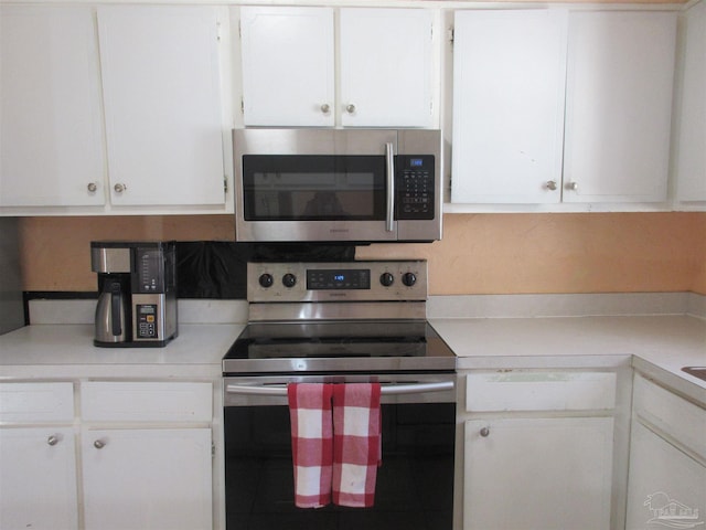 kitchen featuring stainless steel appliances, white cabinets, and light countertops