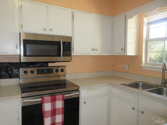 kitchen featuring white cabinets, appliances with stainless steel finishes, light countertops, and a sink