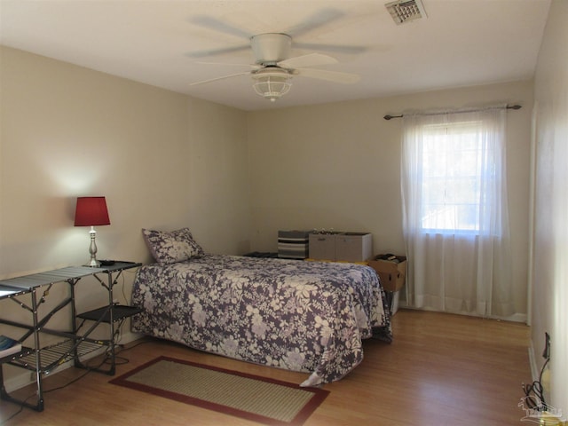 bedroom with light wood-style floors, visible vents, and a ceiling fan