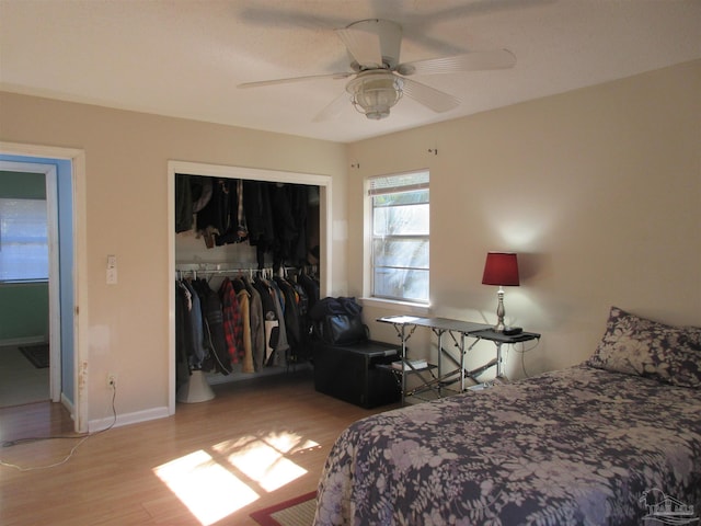 bedroom with a closet, light wood-type flooring, a ceiling fan, and baseboards