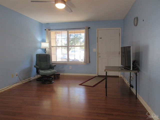 sitting room with a ceiling fan, dark wood-style flooring, and baseboards