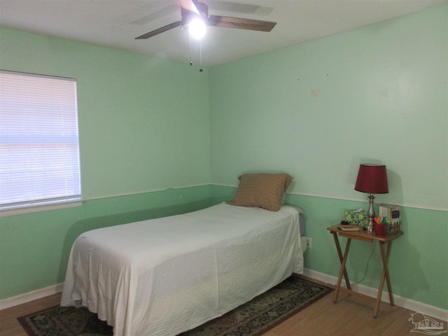 bedroom with ceiling fan, wood finished floors, and baseboards