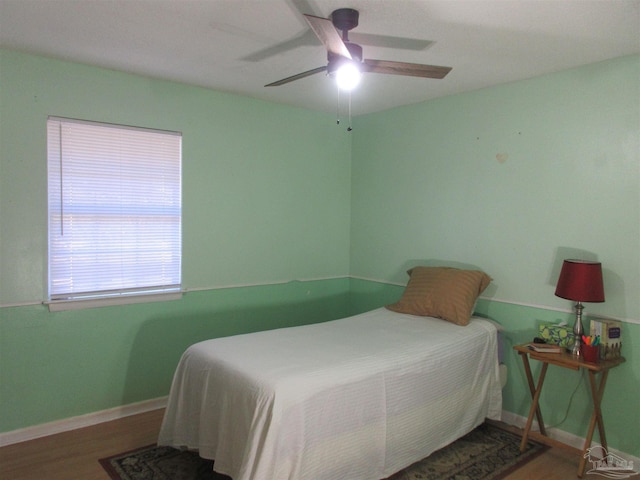 bedroom featuring ceiling fan, wood finished floors, and baseboards