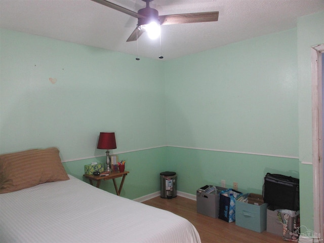 bedroom featuring a ceiling fan, baseboards, and wood finished floors