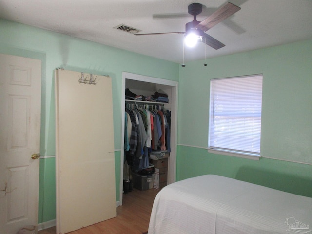 bedroom featuring ceiling fan, a closet, visible vents, and wood finished floors