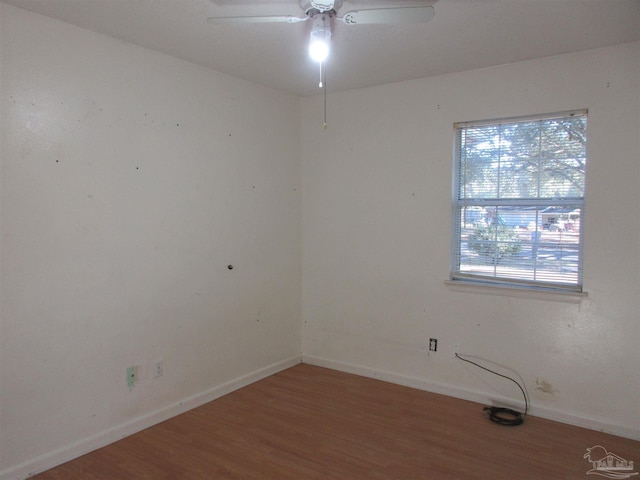 unfurnished room with wood finished floors, a ceiling fan, and baseboards