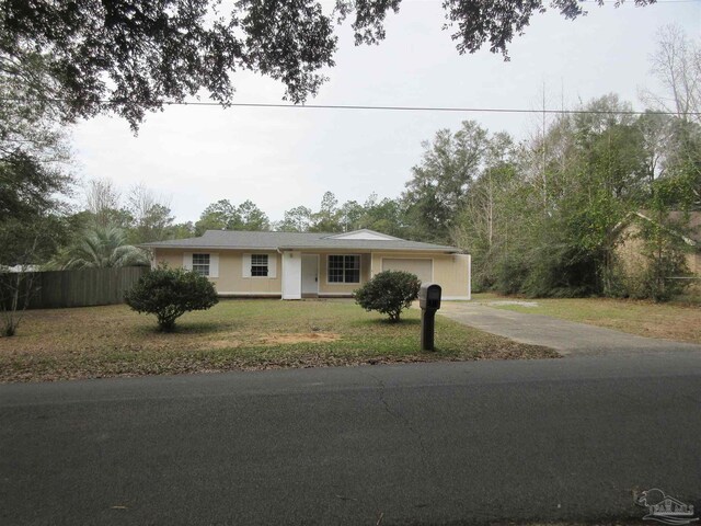 ranch-style house featuring a front yard, driveway, an attached garage, and fence