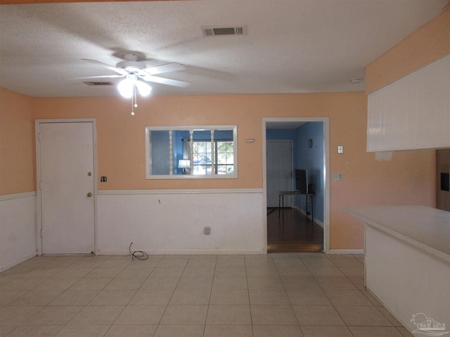 unfurnished room featuring visible vents, ceiling fan, a textured ceiling, and light tile patterned flooring