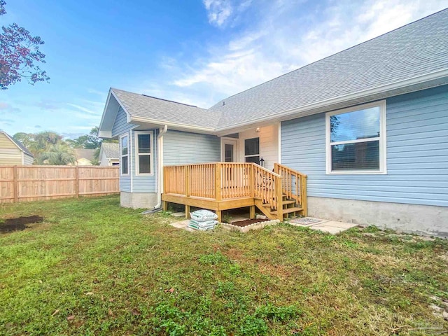 back of property with a wooden deck and a yard