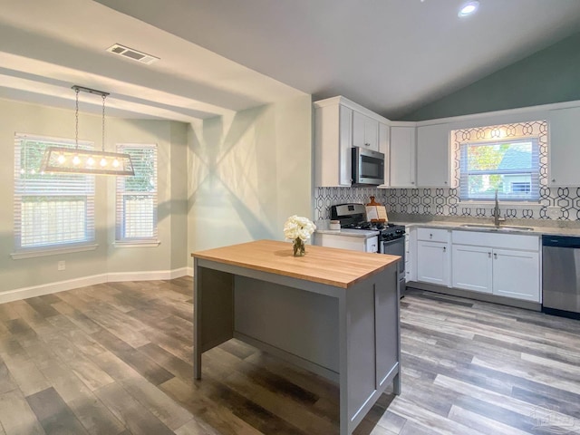 kitchen featuring appliances with stainless steel finishes, white cabinets, sink, and decorative light fixtures