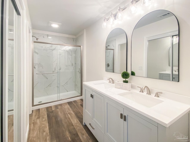 bathroom with wood-type flooring, a shower with door, and vanity