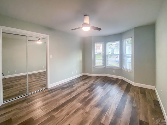 unfurnished bedroom with ceiling fan, dark hardwood / wood-style floors, and a closet