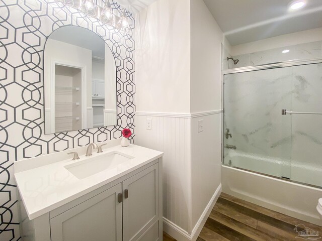 bathroom featuring wood-type flooring, bath / shower combo with glass door, and vanity