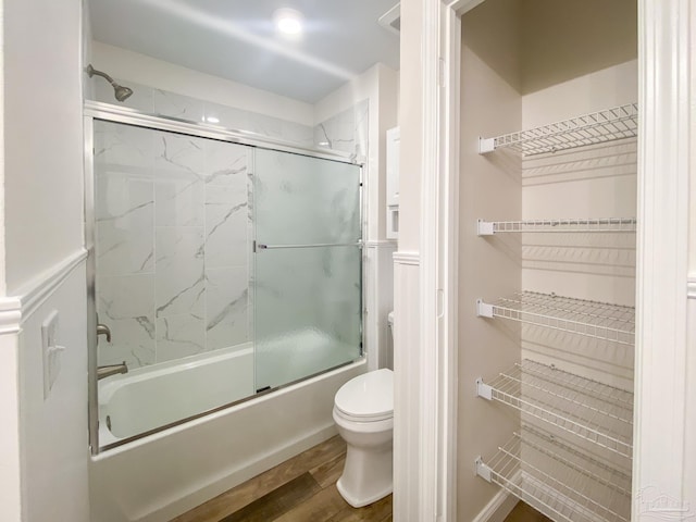 bathroom with wood-type flooring, toilet, and combined bath / shower with glass door